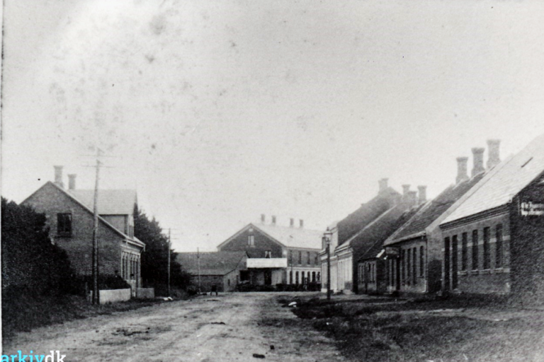Da Ulfkjær blev til Ulfborg</br>Ulfborg Gæstgivergård med hestestald og krostue set fra Harbogade ca. 1900-1910. Til venstre Harbogade 8, som blev bygget i 1898.og stadigvæk eksisterer.<br />Kilde: Ulfborg lokalhistorisk arkiv